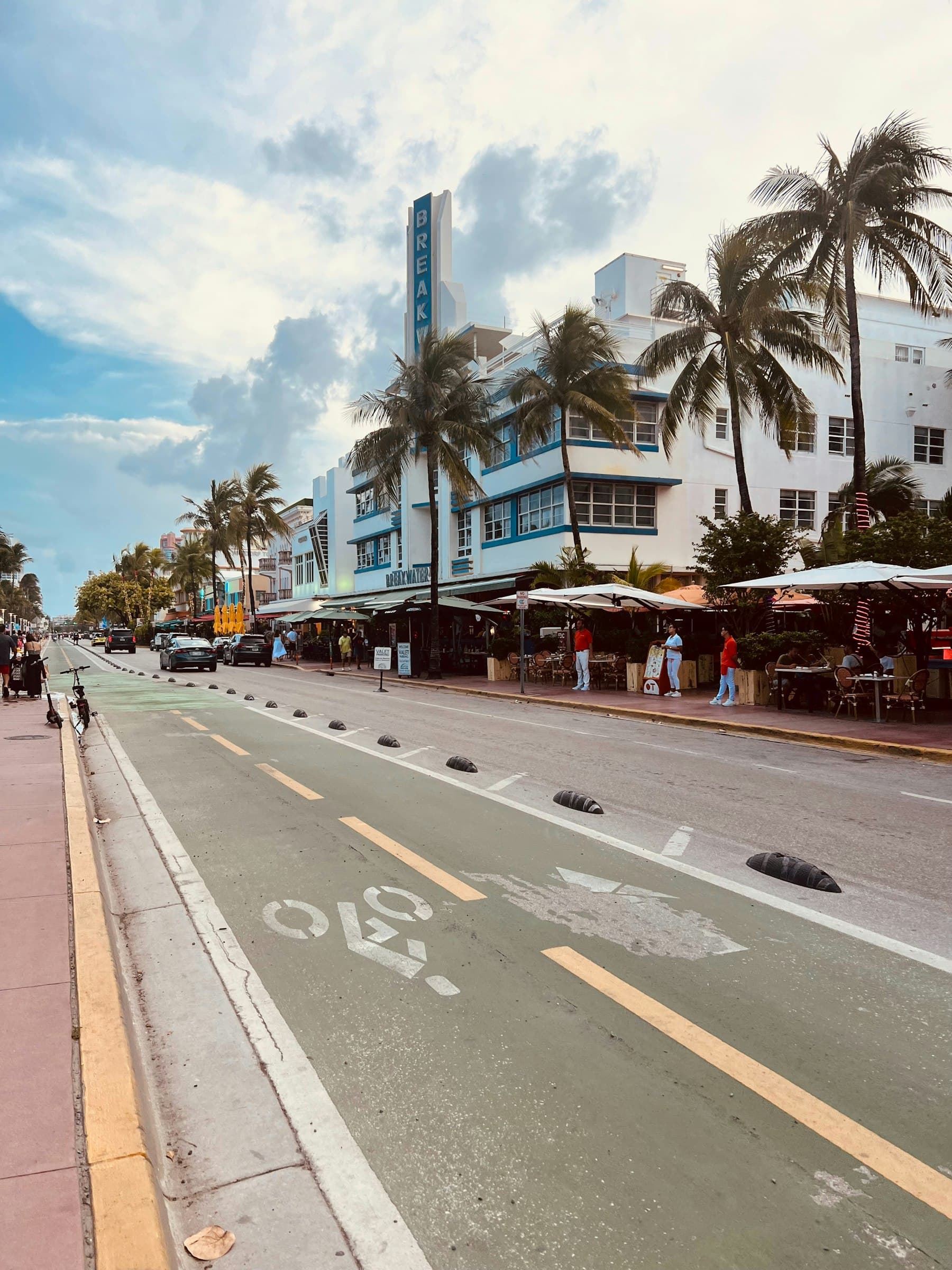 Palm-lined coastal city street with pastel art deco storefronts under a bright Florida sky